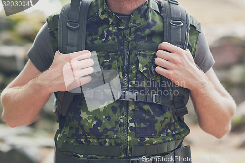 Image of close up of young soldier with backpack in forest