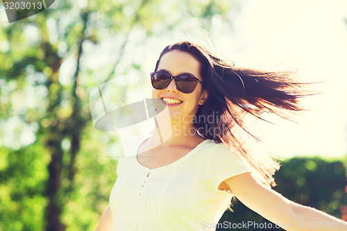 Image of smiling young woman with sunglasses in park