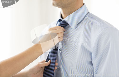 Image of close up of woman hands adjusting tie on mans neck