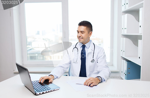 Image of smiling male doctor with laptop in medical office