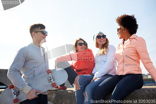 Image of happy teenage friends with longboard on street