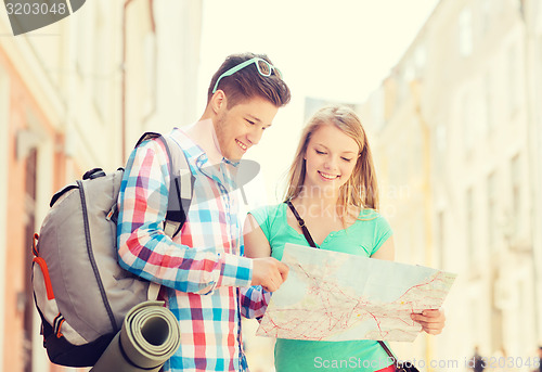 Image of smiling couple with map and backpack in city