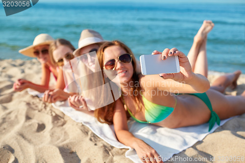 Image of close up of smiling women with smartphone on beach