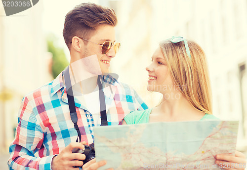 Image of smiling couple with map and photo camera in city