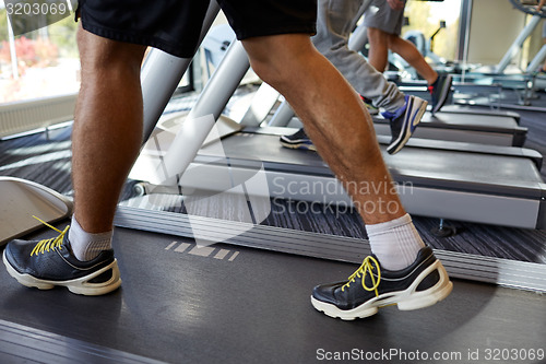 Image of close up of men legs walking on treadmills in gym