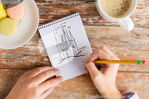 Image of close up of hands drawing in notebook