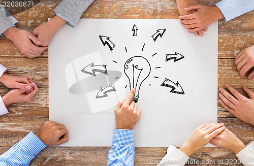 Image of close up of business team pointing to bulb doodle