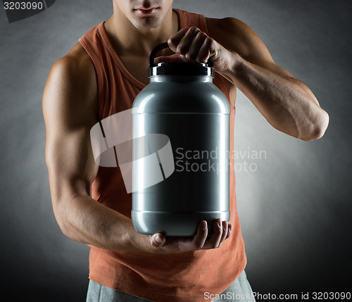 Image of young male bodybuilder holding jar with protein