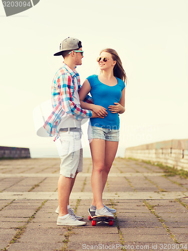 Image of smiling couple with skateboard outdoors