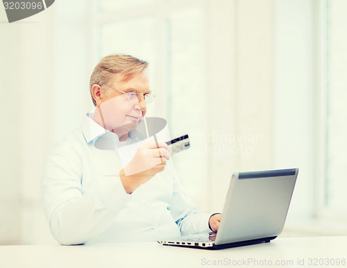 Image of old man with laptop and credit card at home