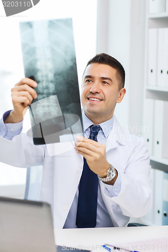 Image of smiling male doctor in white coat looking at x-ray