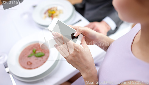 Image of close up of couple with smartphones at restaurant