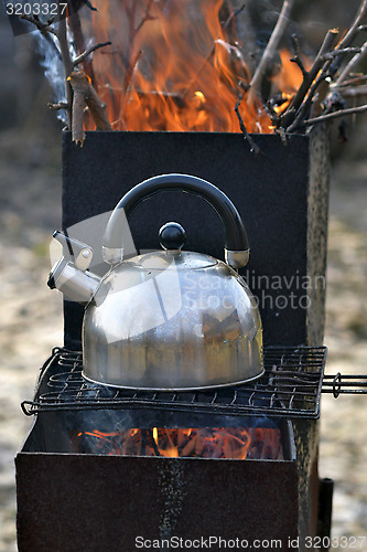 Image of the whistling kettle begins to boil on a brazier