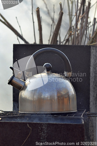 Image of the whistling kettle begins to boil on a brazier.