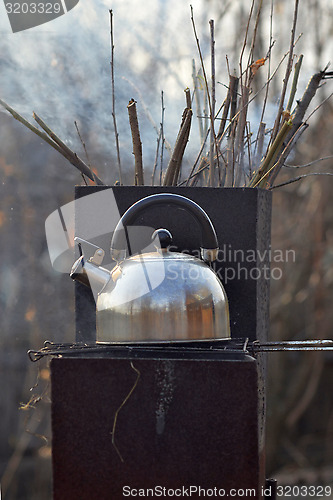 Image of the whistling kettle begins to boil on a brazier.