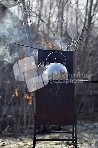 Image of the whistling kettle begins to boil on a brazier