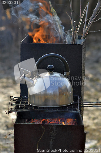 Image of the whistling kettle begins to boil on a brazier.