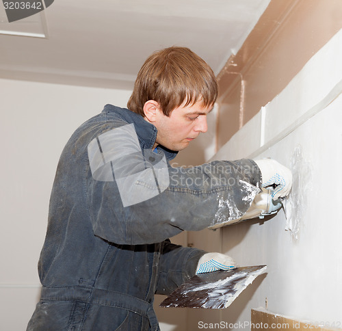 Image of Plasterer at indoor renovation decoration with putty knife