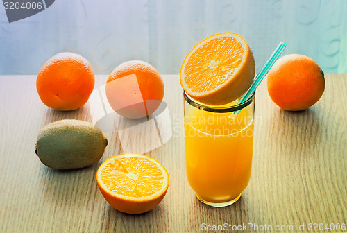 Image of Orange juice in a glass and oranges on the table.