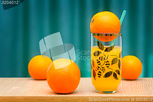 Image of Orange juice in a glass and oranges on the table.