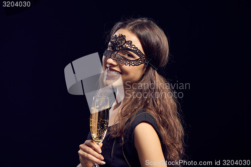 Image of Happe woman in mask holding glass with champagne
