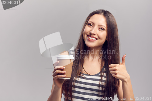 Image of Woman drinking hot drink from disposable paper cup