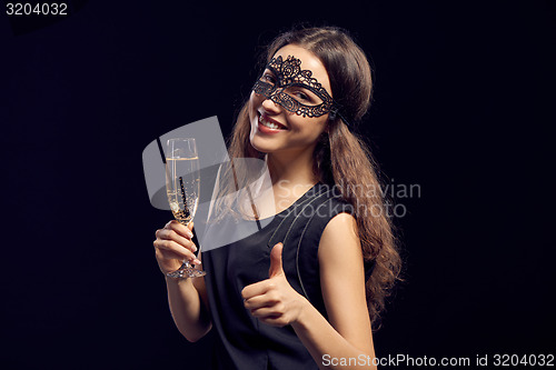 Image of Happe woman in mask holding glass with champagne