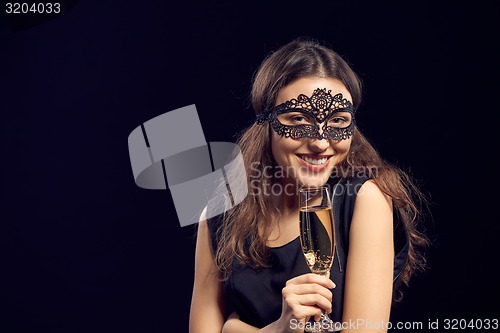 Image of Happe woman in mask holding glass with champagne