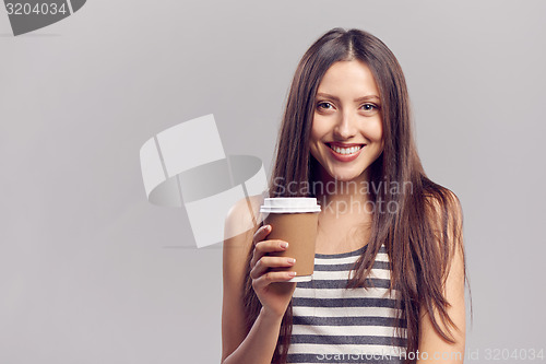 Image of Woman drinking hot drink from disposable paper cup
