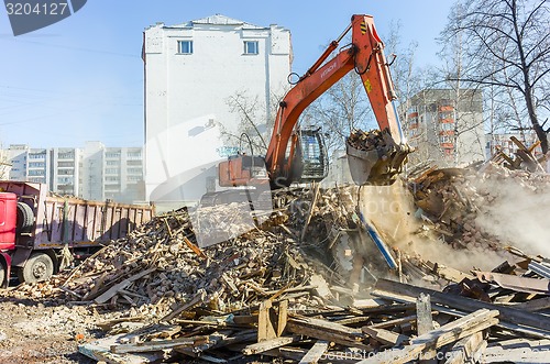 Image of Excavator loads garbage from demolished house