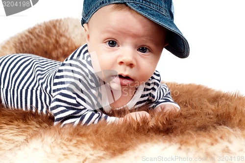 Image of Portrait of adorable child in hat lying on fur