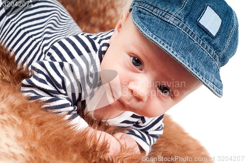 Image of Portrait of adorable baby in cap lying on fur