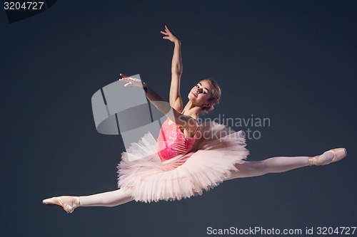 Image of Beautiful female ballet dancer on a grey background. Ballerina is wearing  pink tutu and pointe shoes.