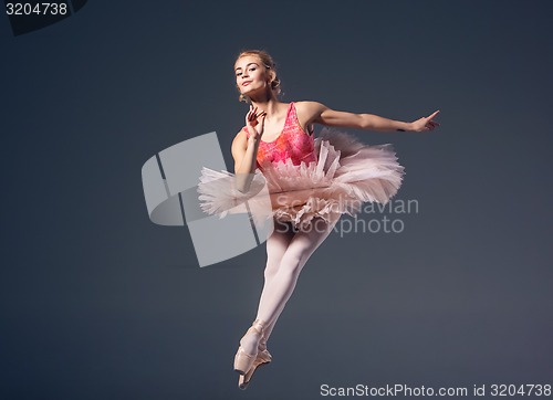 Image of Beautiful female ballet dancer on a grey background. Ballerina is wearing  pink tutu and pointe shoes.