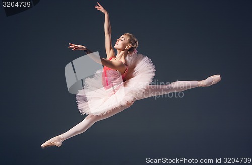 Image of Beautiful female ballet dancer on a grey background. Ballerina is wearing  pink tutu and pointe shoes.