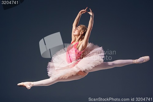 Image of Beautiful female ballet dancer on a grey background. Ballerina is wearing  pink tutu and pointe shoes.