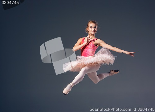 Image of Beautiful female ballet dancer on a grey background. Ballerina is wearing  pink tutu and pointe shoes.