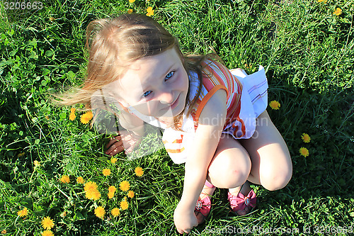 Image of little girl lying on the grass with dandelions