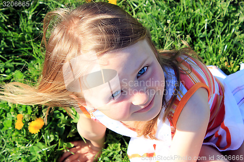 Image of little girl lying on the grass with dandelions