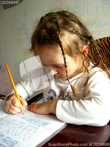 Image of schoolgirl learns lessons at the table