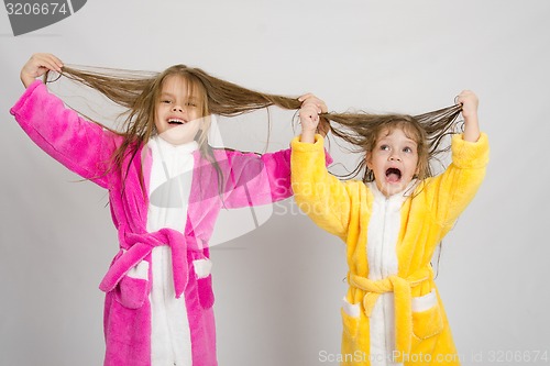 Image of Two girls having fun in dressing gowns keep wet hair