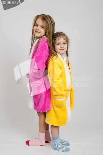 Image of Two girls in dressing gowns stand back to back 