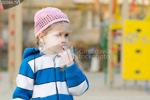 Image of Girl sucks a finger on the playground