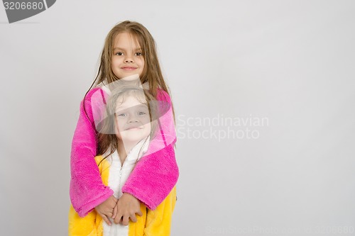 Image of Girl in bathrobe hugging her sister a bathrobe