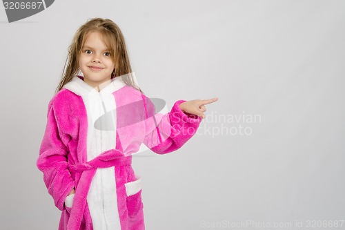 Image of Six year old girl in bathrobe pointing at empty space