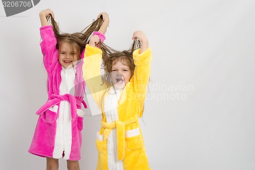 Image of Two girls in the bath robes raised their wet hair