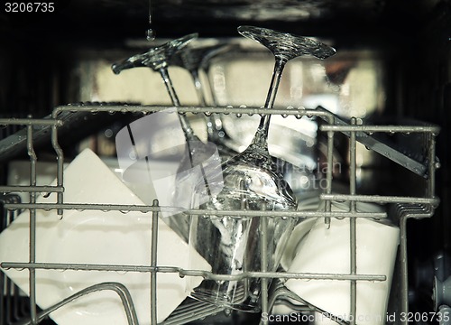 Image of details of open dishwasher, utensils with drops in during washin