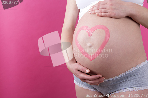 Image of Closeup of a pregnant woman with pink heart on her belly