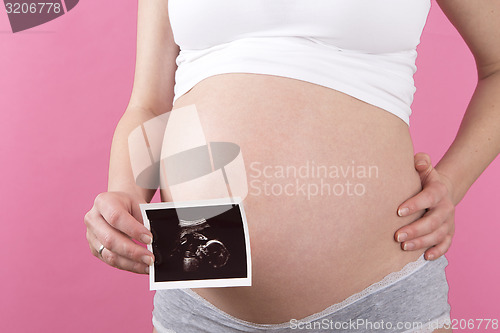 Image of Closeup of a pregnant woman with an ultrasound picture in her ha