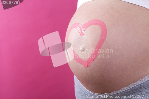 Image of Closeup of a pregnant woman with pink heart on her belly